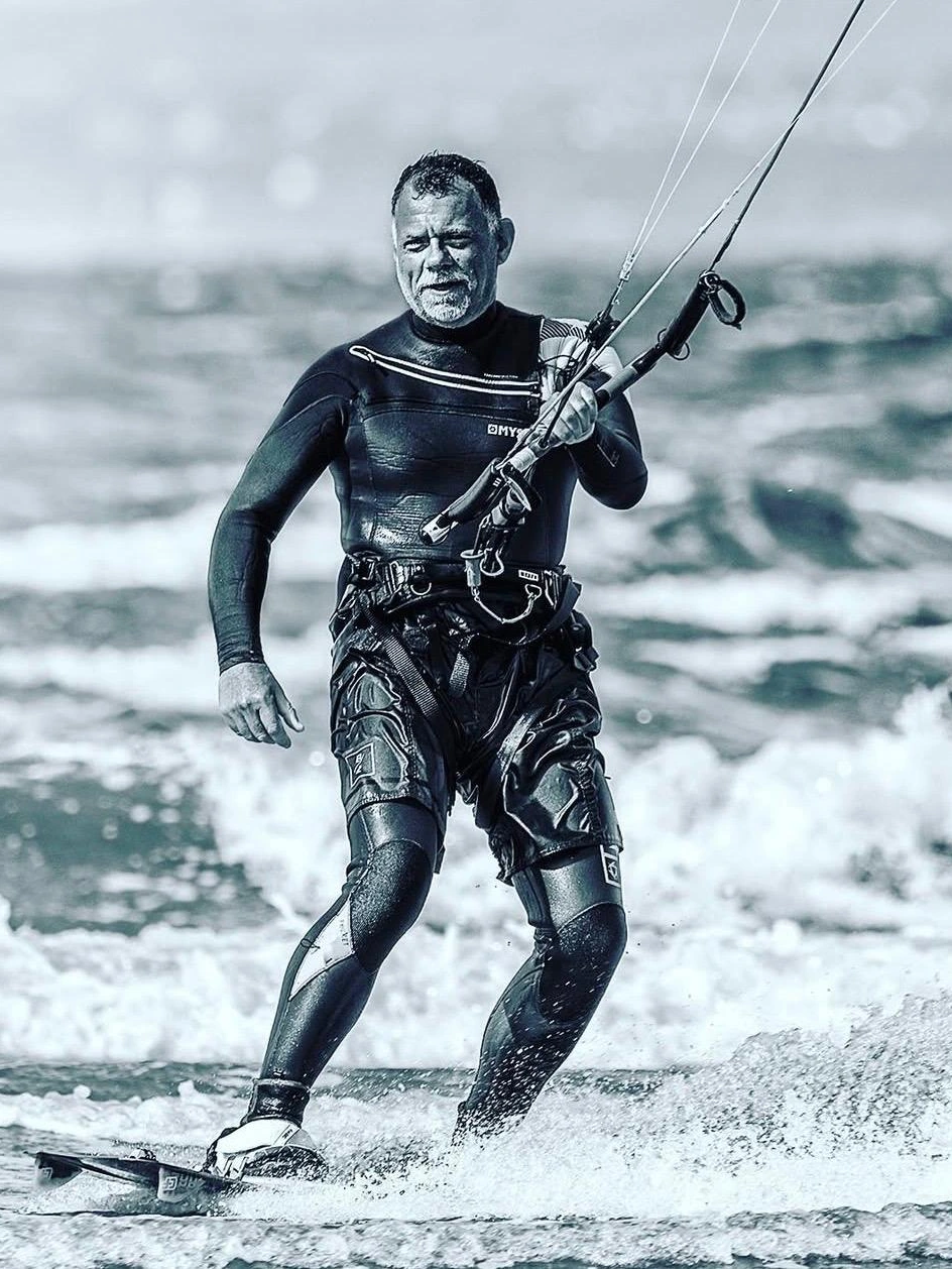 Kitesurfer walking from the water holding a control bar